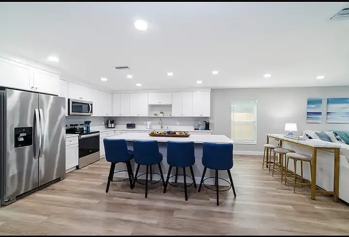The kitchen is bright and open with 4 bar stools at the island and 3 more at the console table.