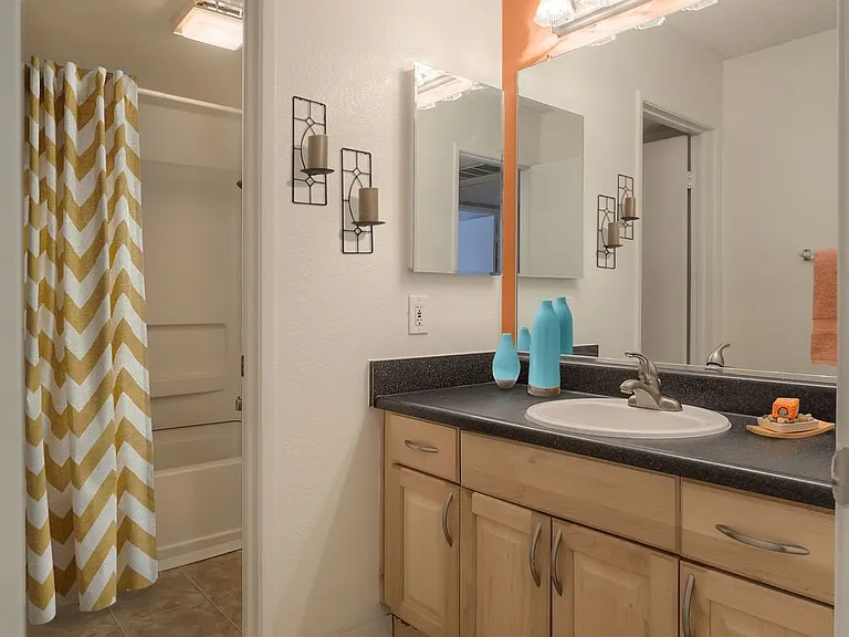 Baths with black laminate countertops and maple cabinetry