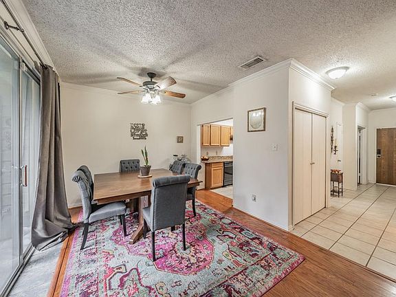 Dining room with ceiling fan, ornamental molding, light hardwood / wood-style flooring, and a textured ceiling