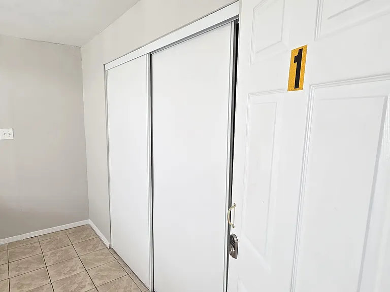 Entry area with tile flooring and a sliding closet for convenient storage near the room access door.