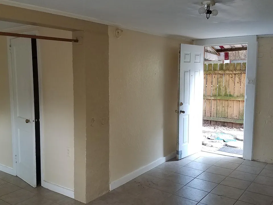 Shooting from corner of living room with bedroom on left, front door is open.