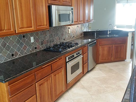 Kitchen with cherry cabinets, gas range and microwave oven.