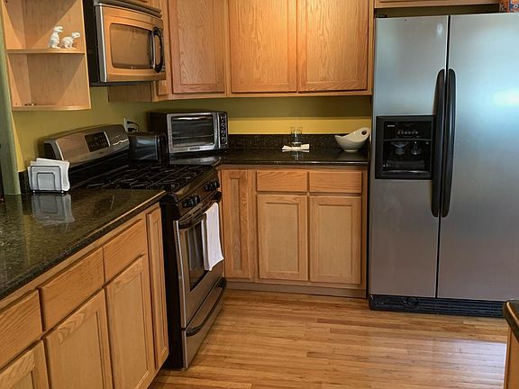 Beautiful wood cabinets, granite countertops, black/stainless steel appliances and hardwood floors in the kitchen.