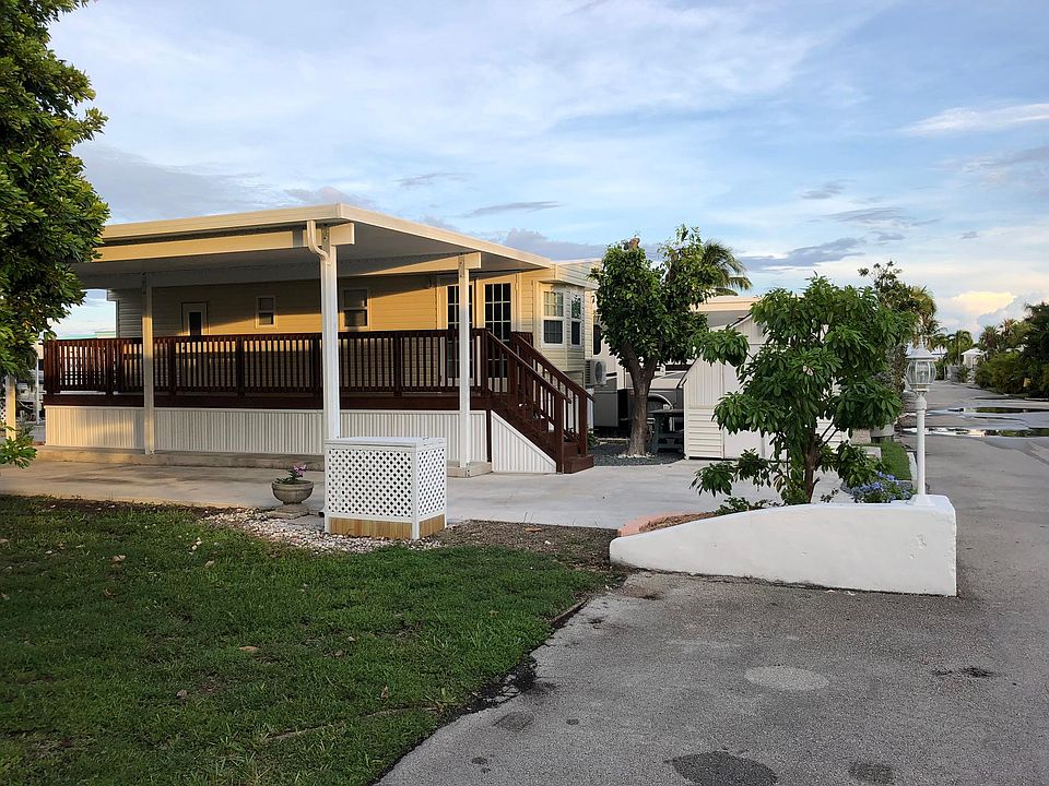 Two car, covered parking with an entrance at either side of the driveway. The white wall is also a part of this property with a lamp and garden. Garden is on an auto drip water system.