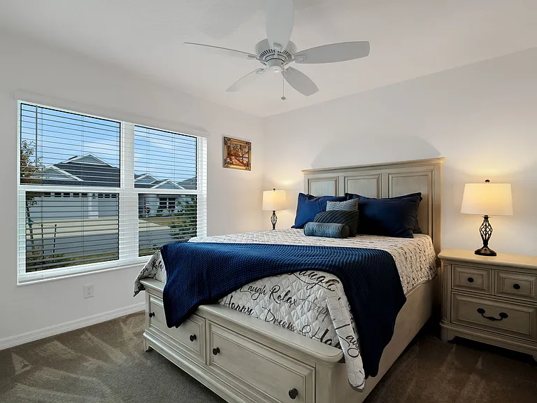 Primary Bedroom with a View of the front yard flowerbed and a Ceiling Fan.