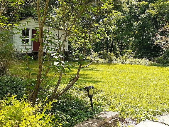 Photo of backyard from apartment entrance. White outbuilding is historic - built during the Civil War era (used for gardening supplies & bike storage).
