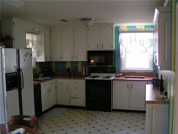 Large kitchen with lots of cabinets, contemporary painting and fixtures. 