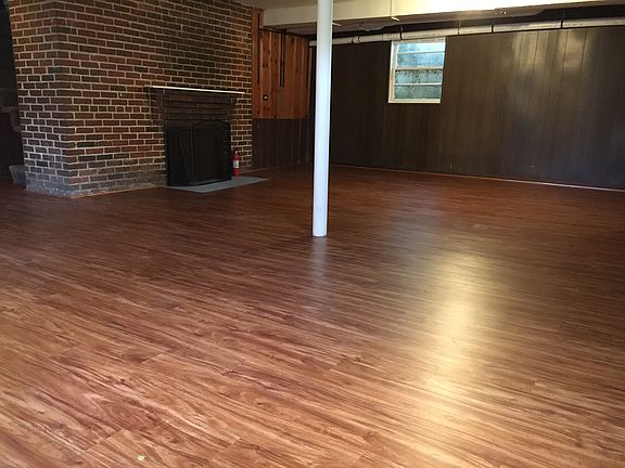 Open floor plan basement with wood burning fireplace.