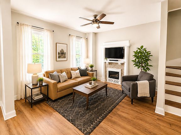 Living room greets you upon entry. The sofa, rug, coffee table, side table, chair, lamp and tv are included.