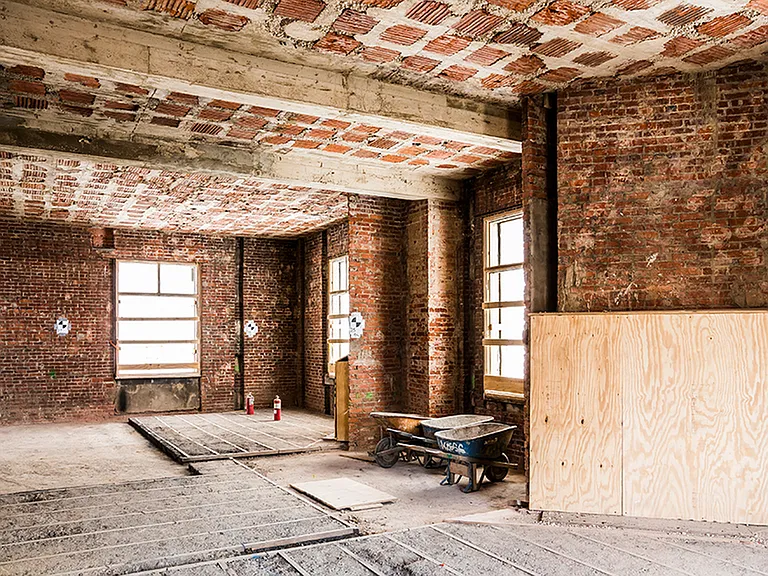 Before: Interior room with exposed brick during renovation
