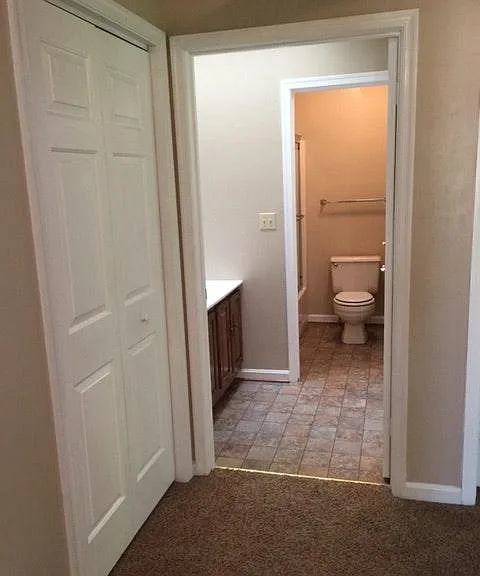 This photo shows the linen closet door and the bathroom, which has a separate door to the bath and toilet area and a door from the hallway into the double sink area, which is open for the photo.