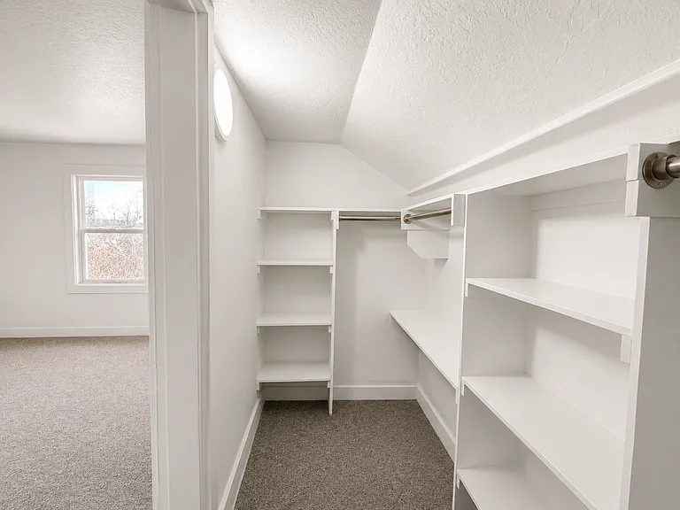 Spacious walk-in closet off the primary bedroom with built-in shelving and plenty of storage.