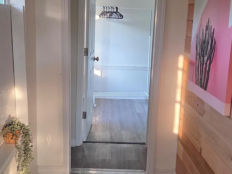 Small hallway/entry area with durable flooring and a door leading to a room with hanging storage space.