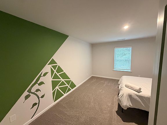 Private carpeted bedroom with a window and overhead lighting, offering space for a bed and additional furniture.