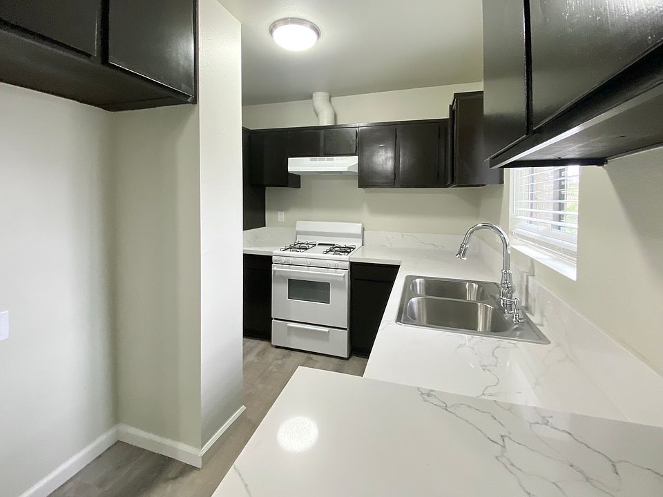 "L" shaped kitchen with new quartz countertops, double sink, and gas range