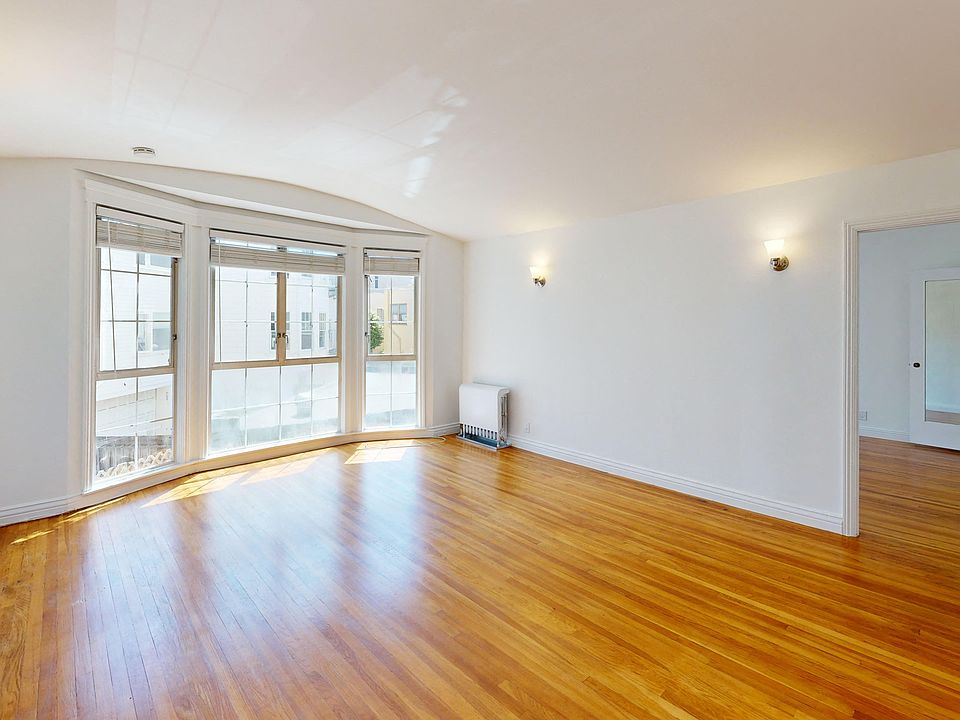 Sunlit living room with a large windows and wood-like floors