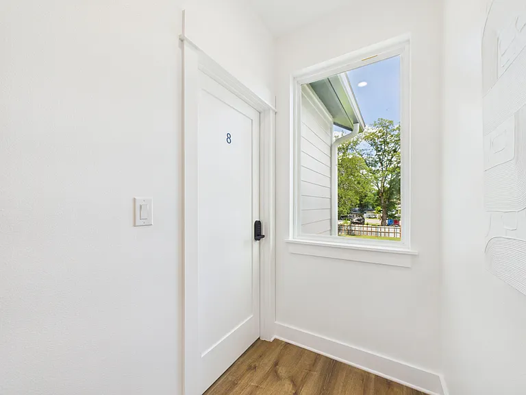 Entry hallway with durable wood-look flooring, a secure door, and a window bringing in natural light and outdoor views.