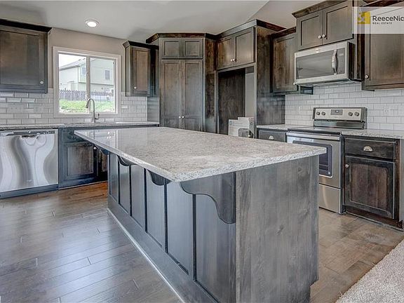 Kitchen offers stainless steel appliances (microwave, dishwasher, electric range), garbage disposal, custom beech cabinetry with crown molding, granite counter tops and tiled backsplash.