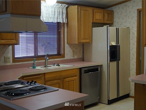 Spacious kitchen with plenty of Oak cabinetry and countertop surface. There is a wall oven to the right and Utility room past the fridge. There you will find another door to the exterior/carport.