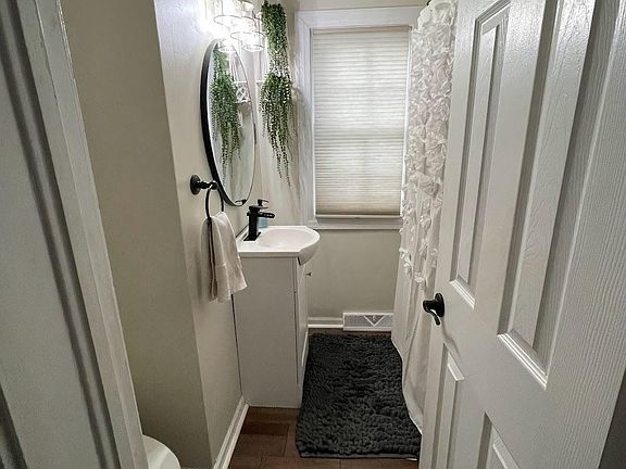 Bathroom recently renovated with brand new vinyl plank flooring, sink, toilet and lighting