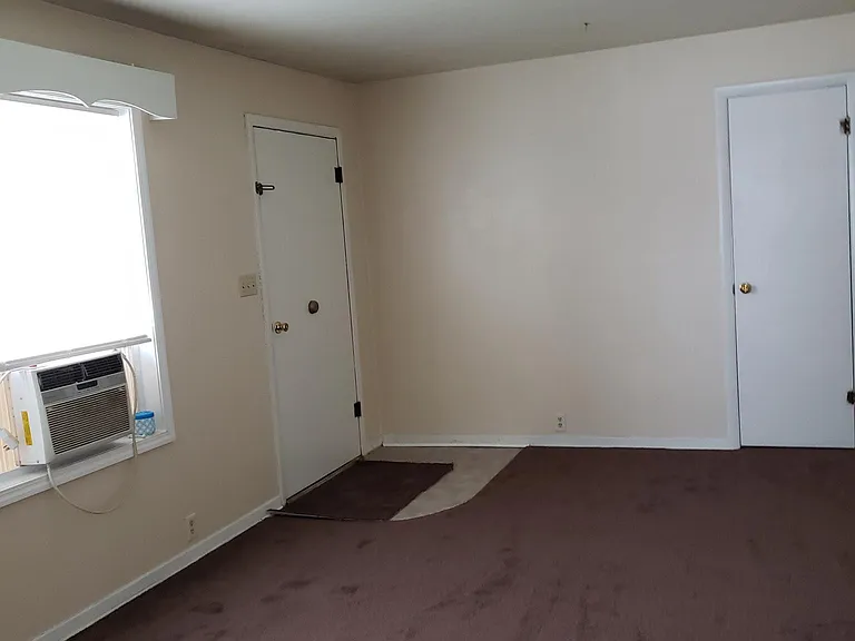 Living room looking at entry foor and coat closet and window ac.