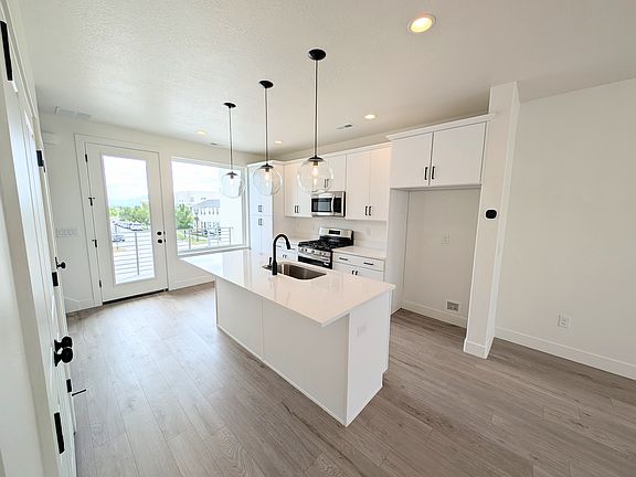 Modern, bright kitchen with white cabinets, stainless steel appliances, a central island with a sink