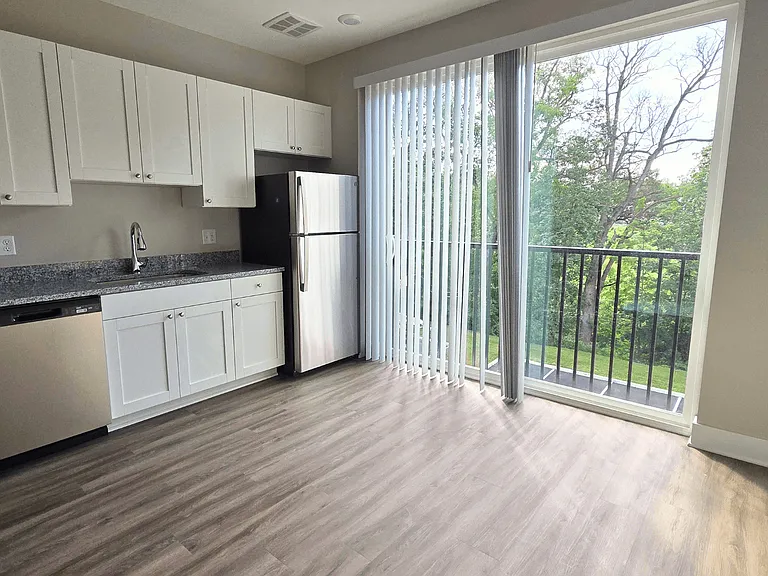 Kitchen and living area with balcony of an available apartment unit at Greenwood Commons Apartments in Delaware, OH.