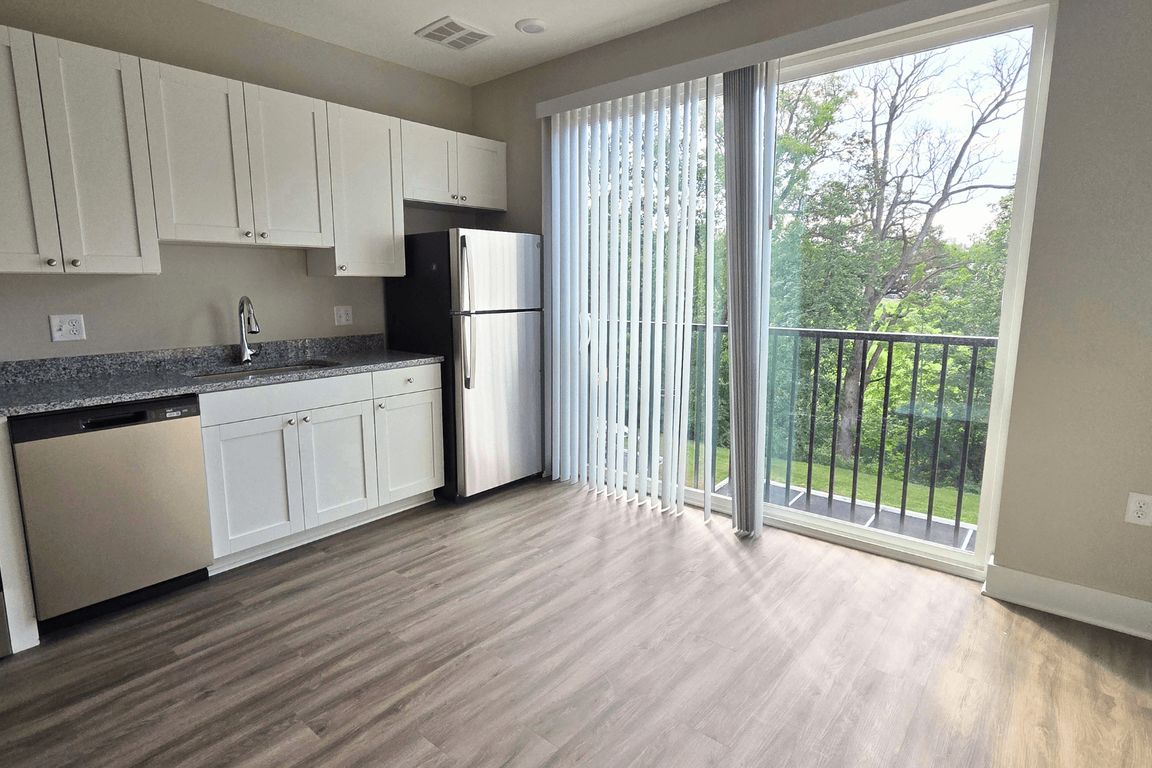 Kitchen and living area with balcony of an available apartment unit at Greenwood Commons Apartments in Delaware, OH.