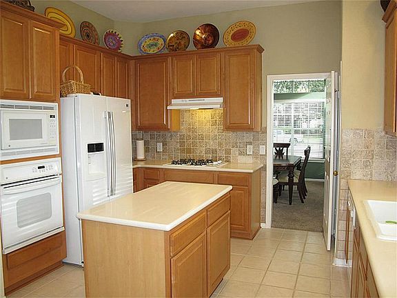 Gourmet island kitchen boasts ceramic tile flooring & backsplash, Corian counters, abundant 42" cabinetry, recessed lighting, & built-in microwave!