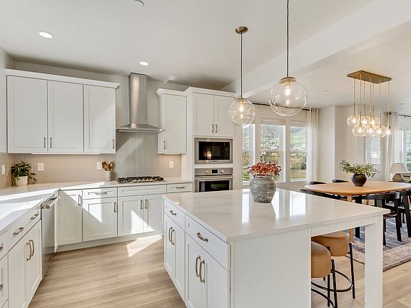 Modern kitchen with white cabinetry, stainless steel appliances, and a center island featuring penda