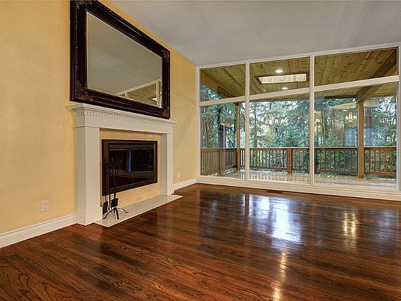 View of the living room with fireplace, covered deck with skylights and recessed lighting.
