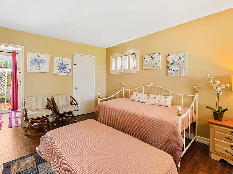 This picture shows the owner suite with day bed, the walk in closet and bathroom with sliding doors leading to the sideyard.
