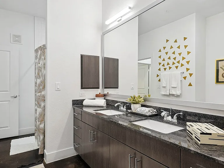 Apartment bathroom with wood-style flooring and double sinks.