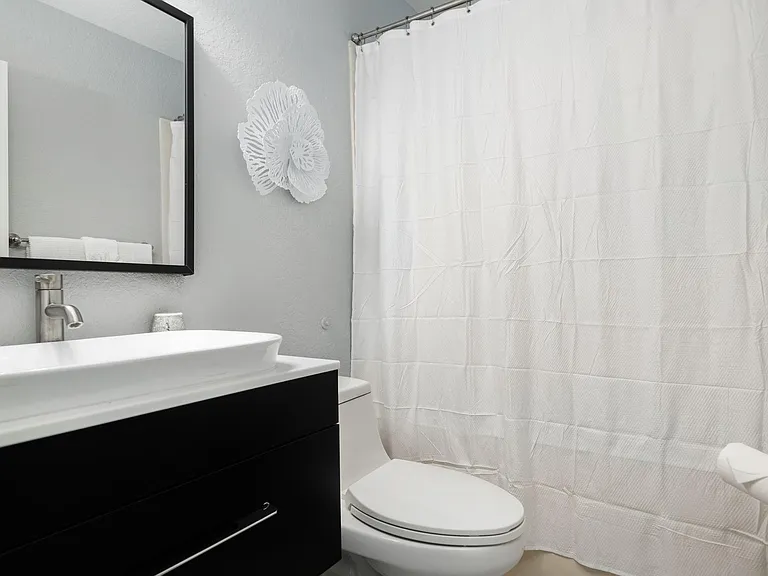 Bath with tub off guest room with king bed.