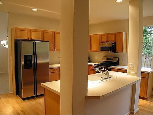 kitchen area with large pantry, stainless appliances, tile counters, 