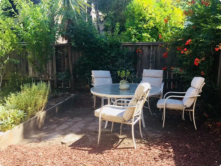 Outdoor seating area fruit trees and vegetable bed.