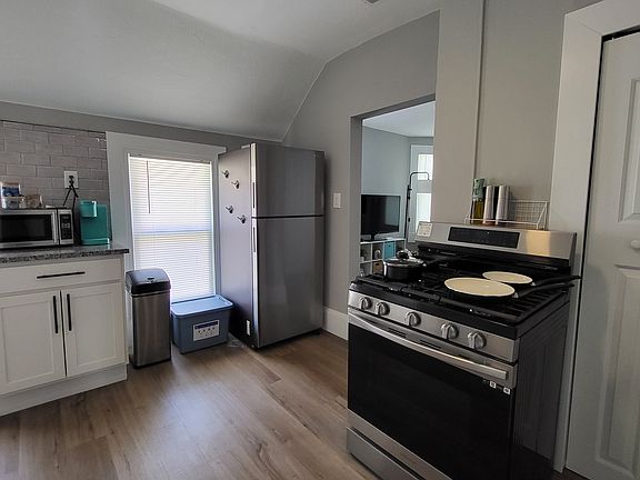 Kitchen area with modern stainless steel appliances (gas range, full size fridge, and small microwave).