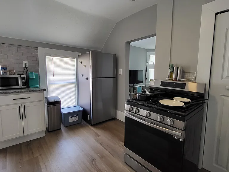 Kitchen area with modern stainless steel appliances (gas range, full size fridge, and small microwave).