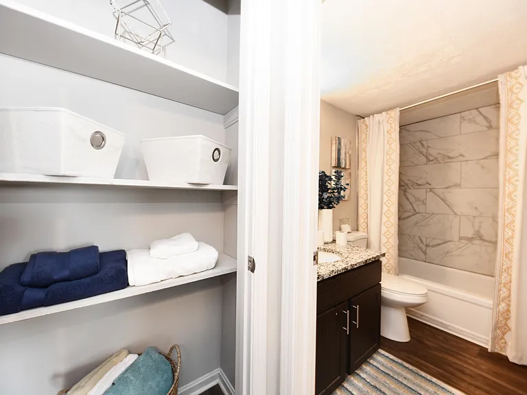 Linen Closet in Bathroom with Granite Counters and Bathtub with Marble Backsplash