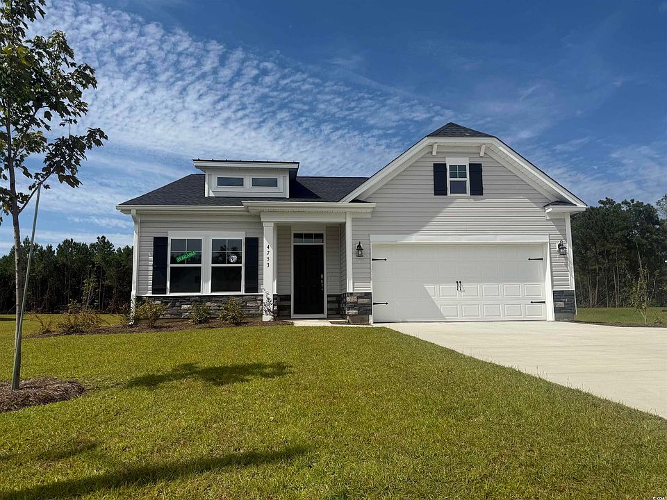 Craftsman-style home with stone siding, driveway, a front yard, a porch, and roof with shingles