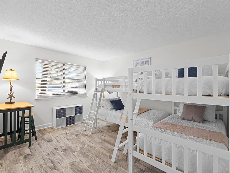 The bunkroom has four twin beds, a smart TV and a desk and stool.