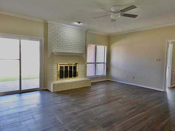 Large and open living room with gas fireplace, ceiling fan, and sliding doors that open to private patio and fenced yard. Fresh flooring and paint from 2024.