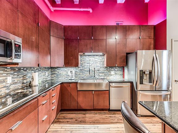 This view really spotlights the plentiful storage, farmhouse sink, dishwasher and refrigerator - all in stainless steel!