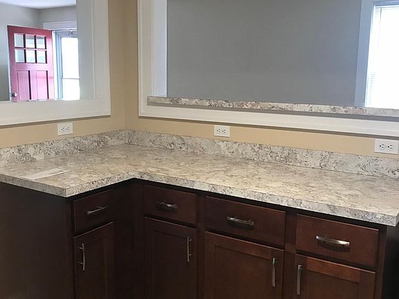 New kitchen cabinets and counters looking into living room and dining area and front entry door.