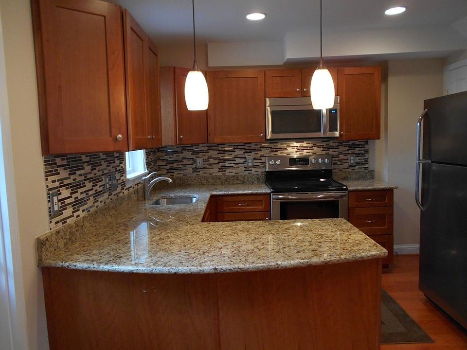 Kitchen has stainless appliances, ample granite countertop working space, and breakfast bar overhang
