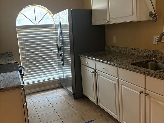 Kitchen with stainless steel appliances. Microwave, refrigerator, dishwasher, flattop convection oven.