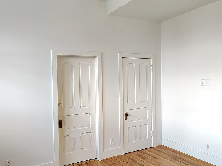 SE bedroom showing private bathroom door on the left, and closet door on the right.