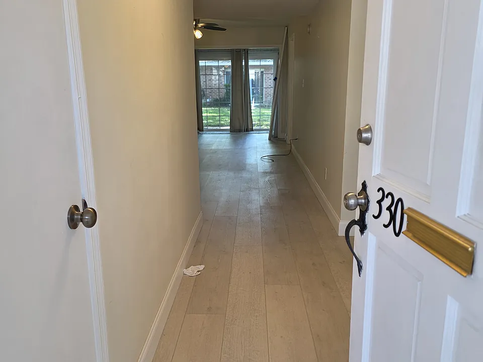 As you walk into the unit there is a coat closet to the left. There's a long hall that would be great for artwork and photos. You can see the sliding glass doors with the view of the grassy common area behind the unit.