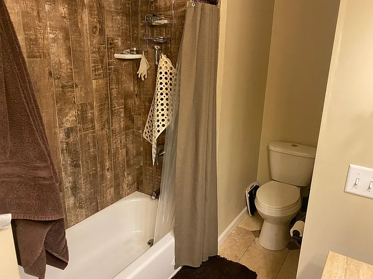 Main bathroom with tub/shower and wood look tile
