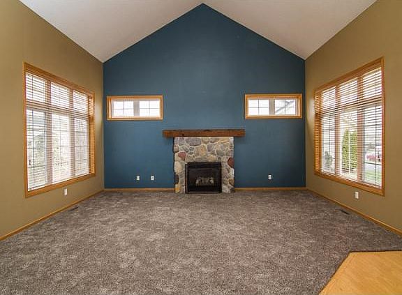 Another view of the fireplace, notice the vaulted ceilings and large windows providing natural light! This room can be viewed from the stairway balcony leading up to the second level.
